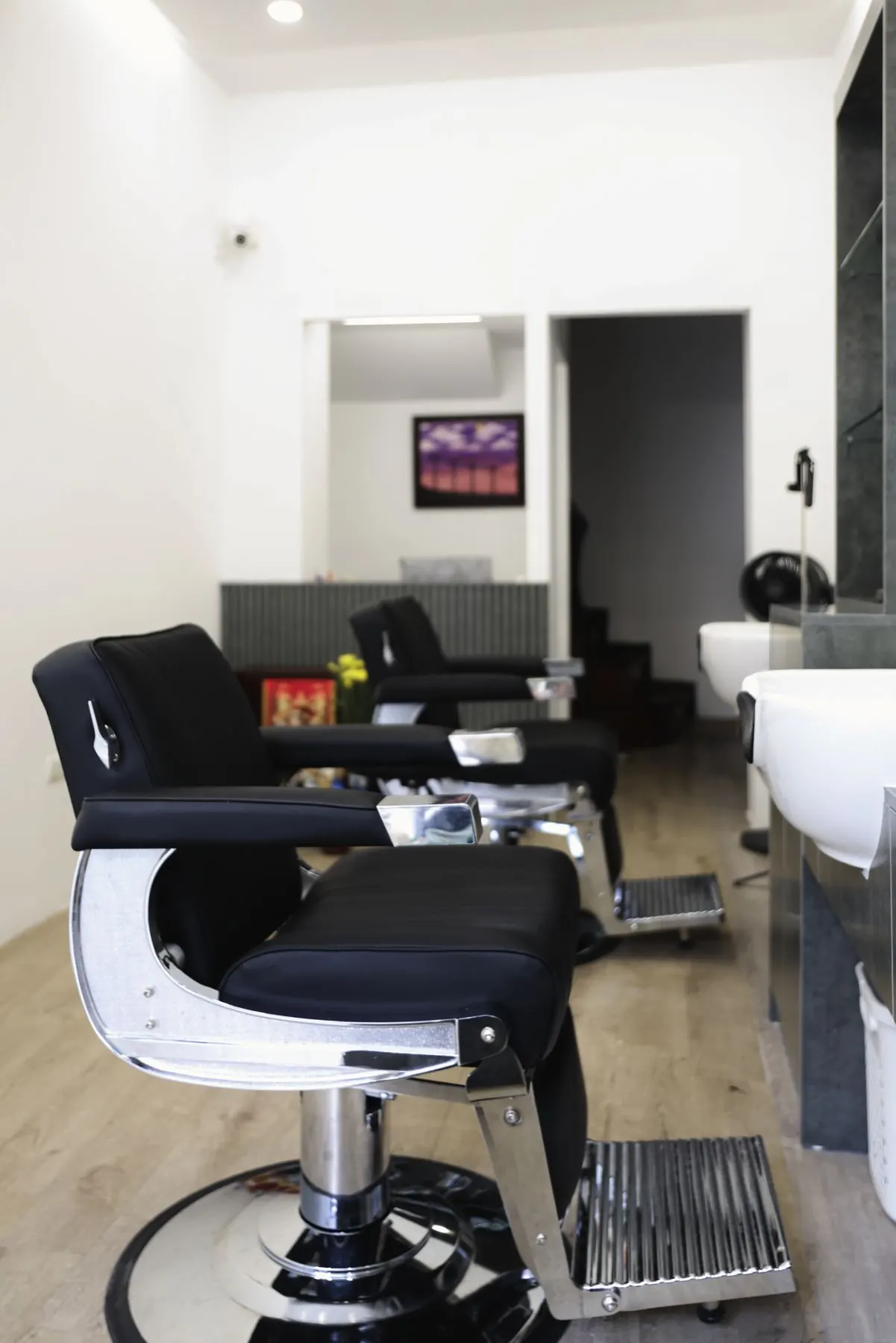 Ghế barber da đen chân xoay, phía sau là khu gội đầu